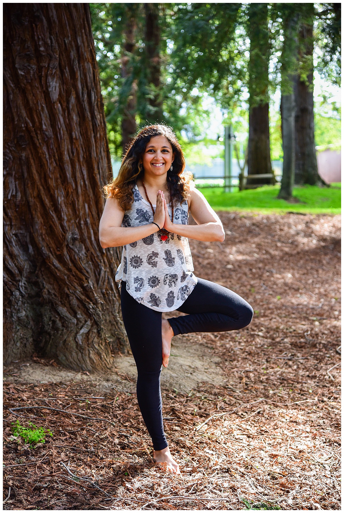 Woman doing yoga tree pose under redwood trees