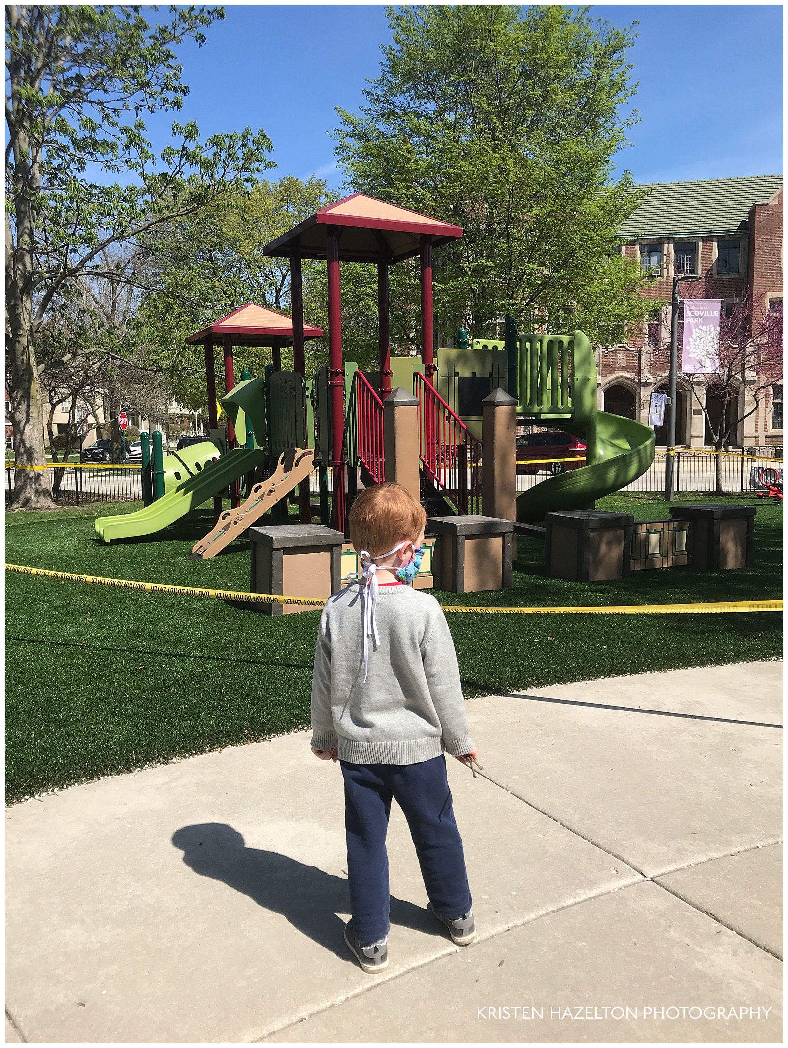 Toddler looking at a playground closed off with warning tape due to the COVID-19 pandemic