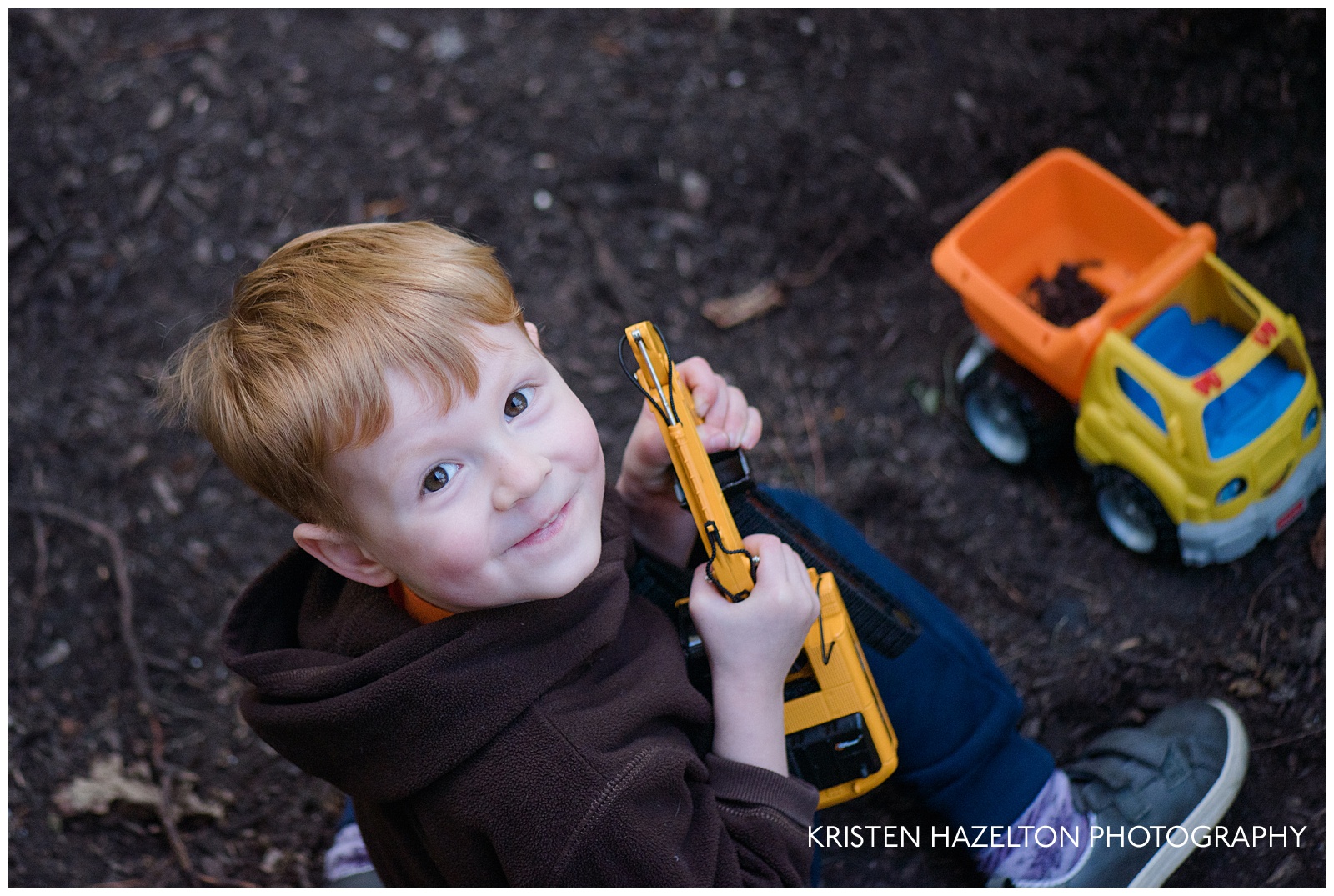 Toddler playing in the dirt with excavator and dump truck toys