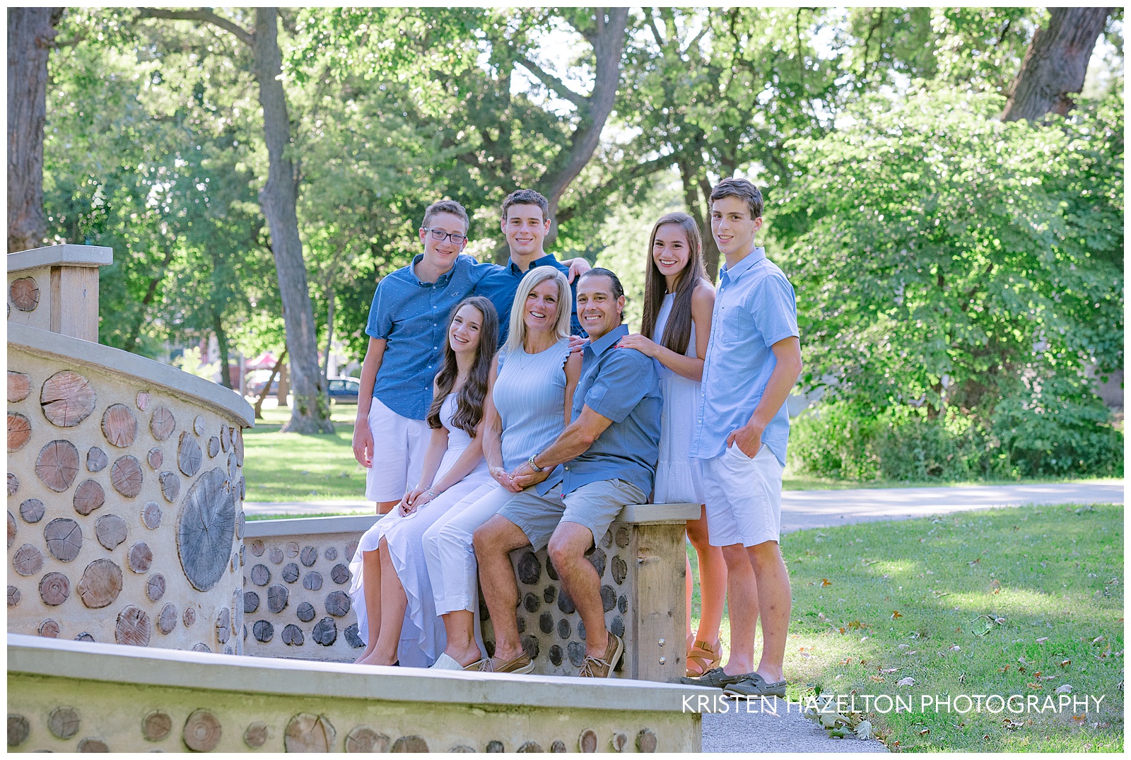 Family of seven sitting on a sculpture for a family portrait
