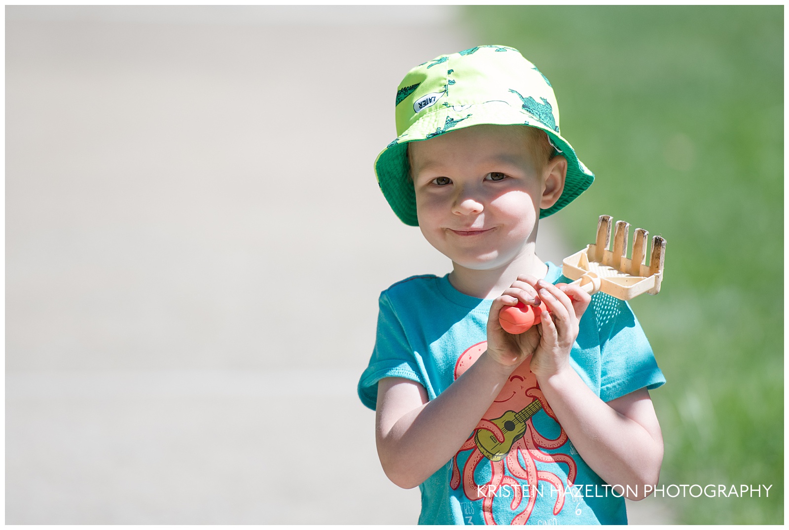 Toddler wearing a hat and holding a small rake