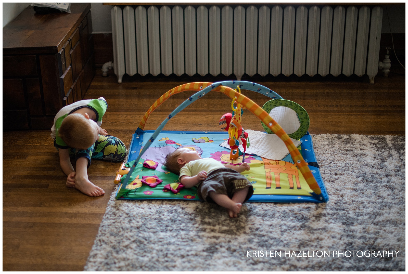 Big brother playing with baby sister on a playmat