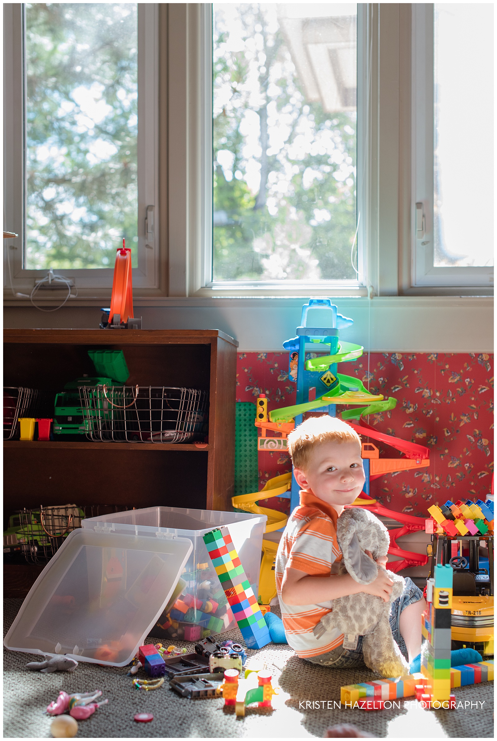 Toddler sitting in a sunbeam and playing in a playroom surrounded by toys