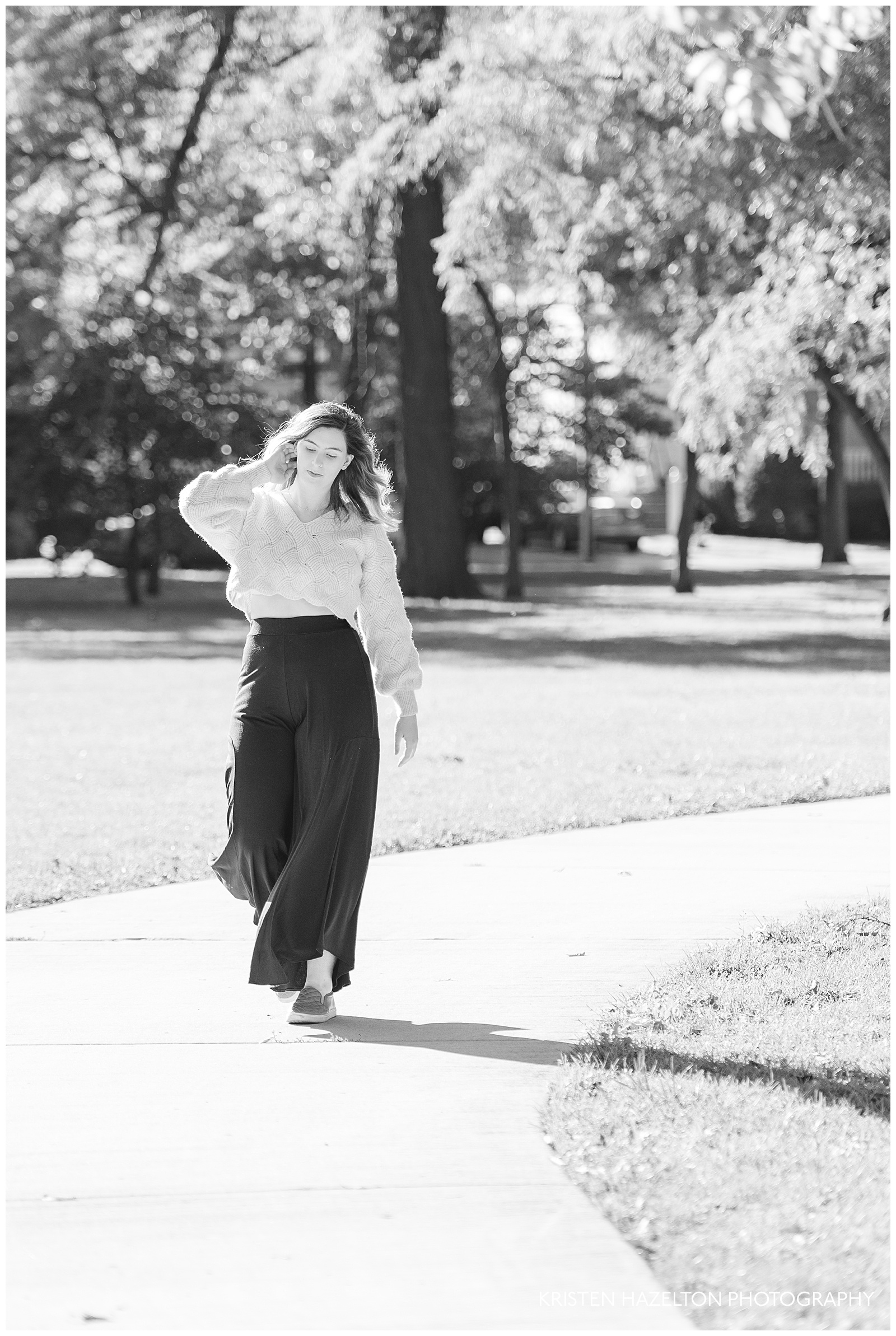 Black and white photo of a college senior walking down a sidewalk