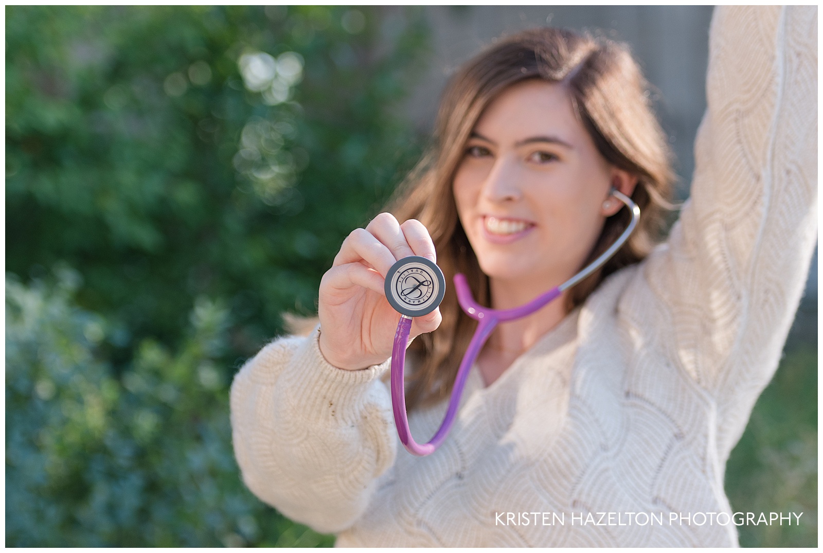 Nursing school senior portrait of a nurse-in-training holding out her stethoscope and cheering