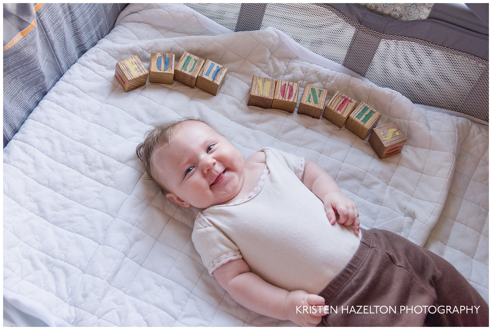 Smiling four month old baby with painted blocks