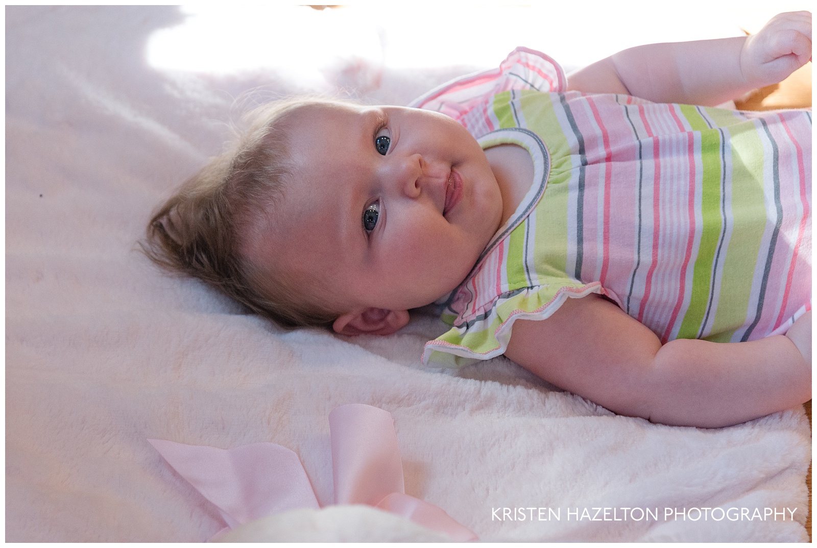 Cheerful four month baby on a pink pillow