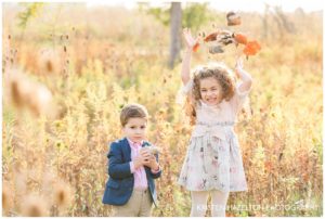 Portraits of a brother and sister throwing leaves in the air