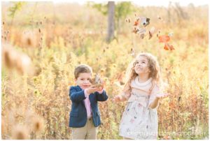 Portraits of a brother and sister throwing leaves in the air