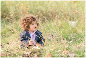 Baby boy delighted by long stalks of grass in a field