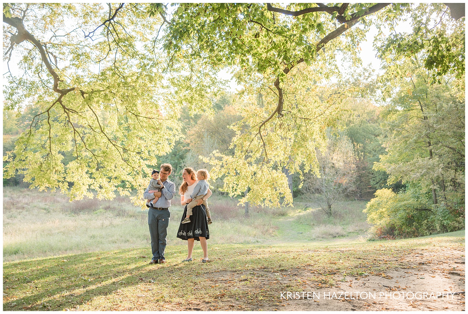 Photo of a Mother and father holding baby and toddler under a tree by Oak Park IL family photographer Kristen Hazelton
