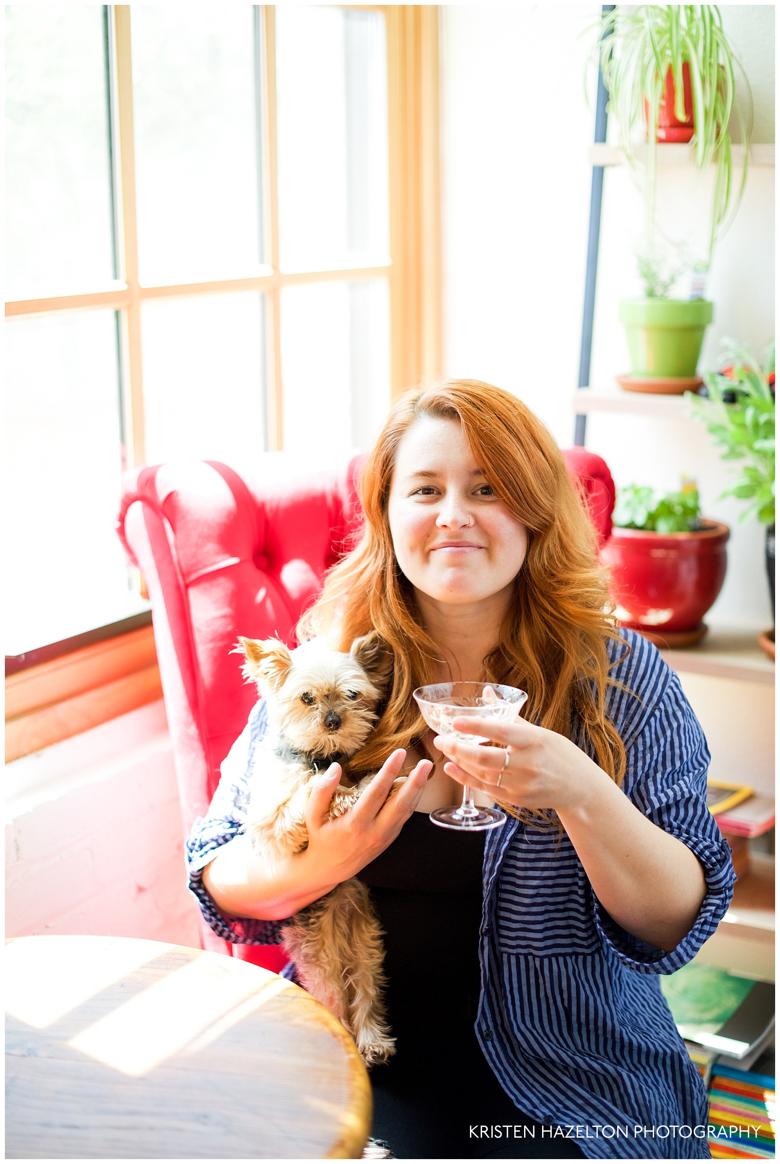 redheaded woman drinking champagne while holding a tiny dog