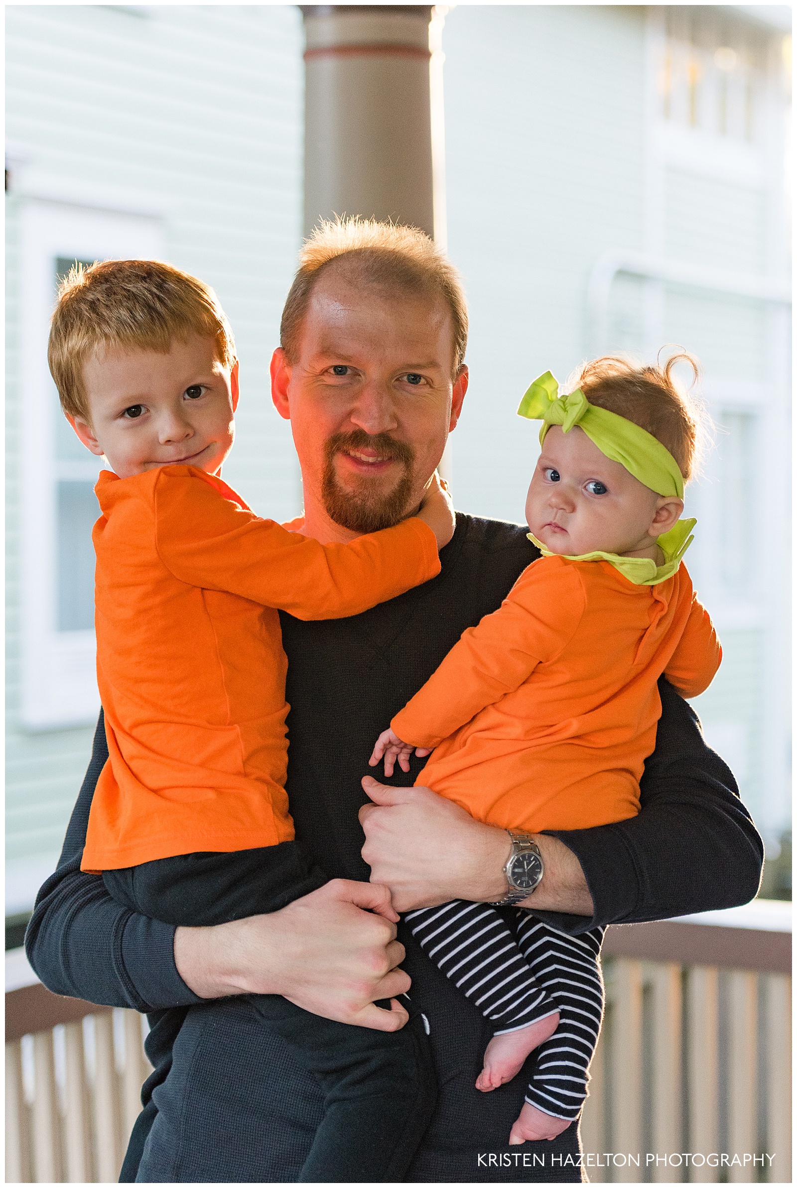 Father holding young children in Halloween clothes