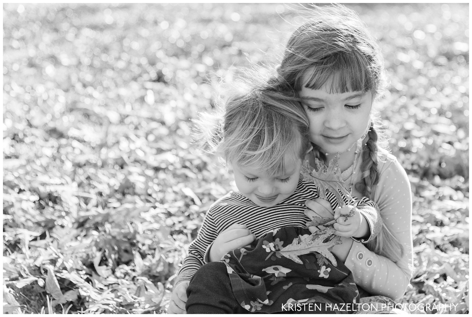Fall family portraits of Two sisters sitting and throwing leaves together
