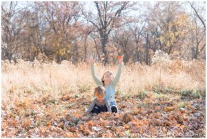 Family portraits of Two sister throwing leaves together