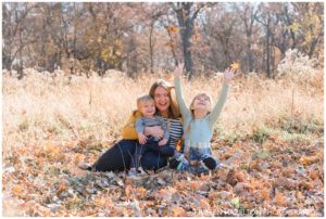 fall portraits of a Mother with daughters throwing leaves