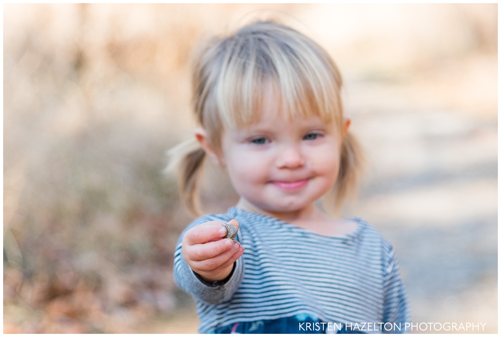 A toddler girl proudly displaying a rock