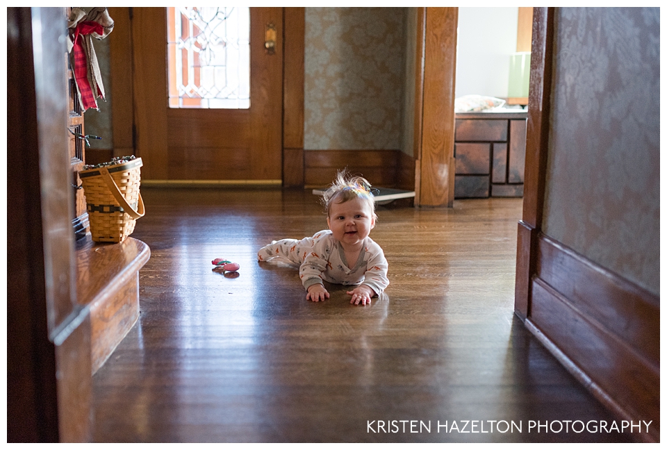 Happy baby on a wood floor with rainbows in her hair
