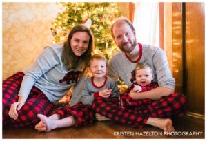 Family of four in matching pajamas in front of a Christmas tree