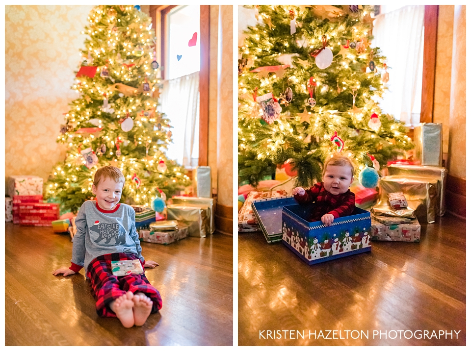 Young boy sitting in front of a Christmas tree, and a baby in a Christmas box in front of the Christmas tree