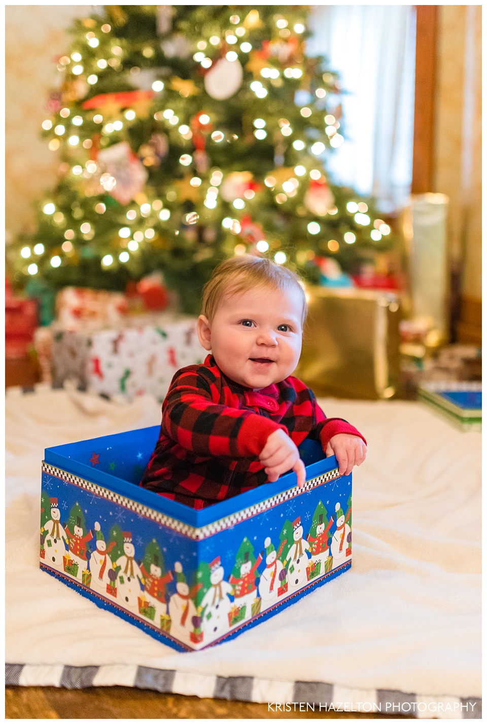 Happy baby in a box in front of the Christmas tree