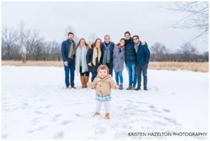 Photo of happy toddler standing in front of extended family