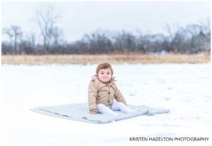 Toddler boy sitting on a blanket in the snow