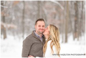 Wife kissing husband in snowy woods