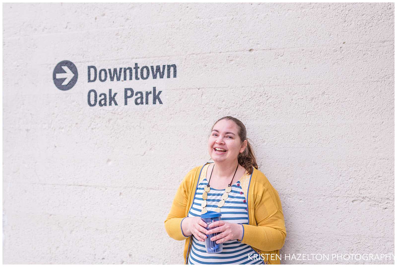 Woman laughing next to a sign saying "downtown Oak Park"