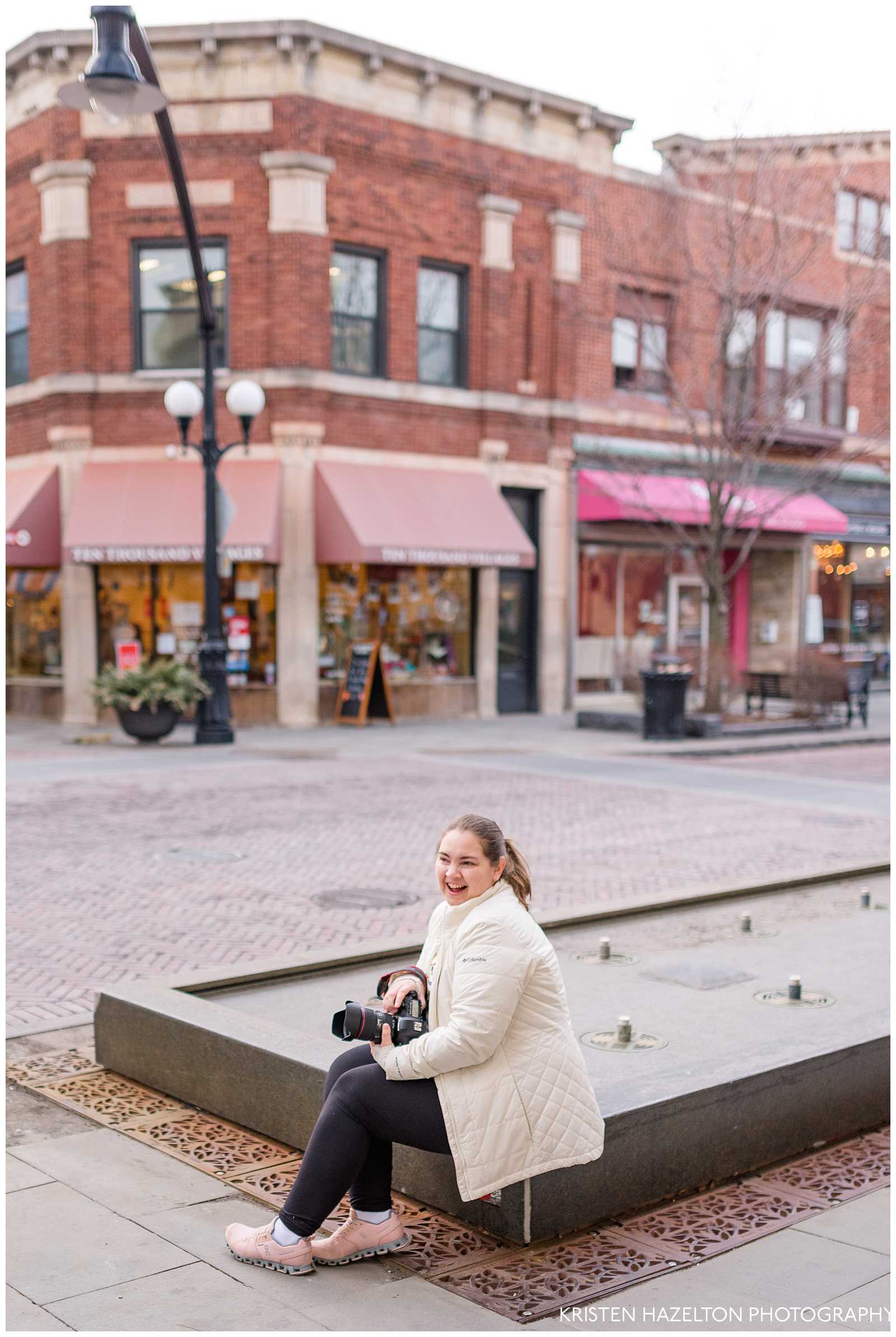 woman in white coat sitting at the Marion St fountain in downtown Oak Park, IL