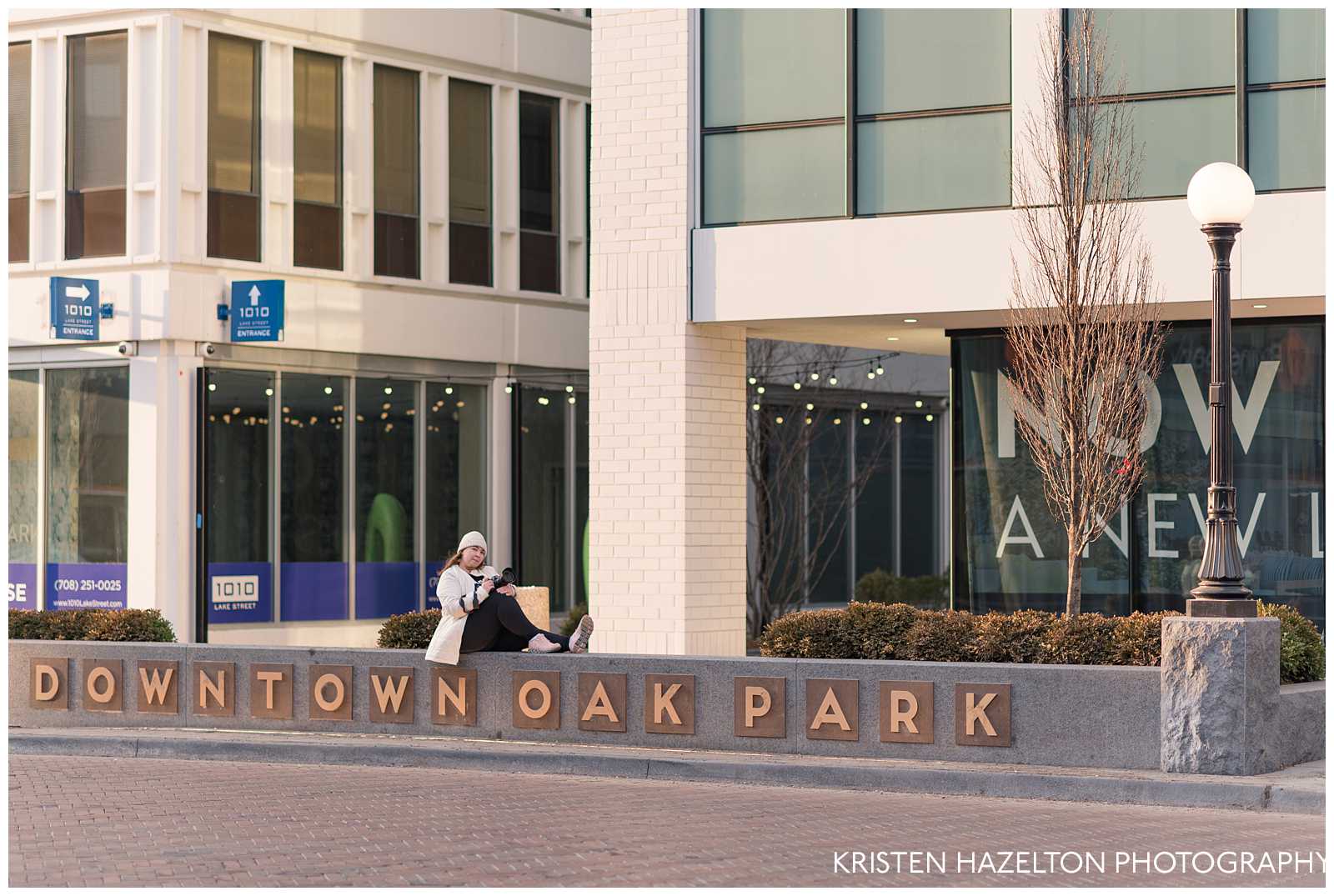 Tina Harle sitting on a sign that says Downtown Oak Park