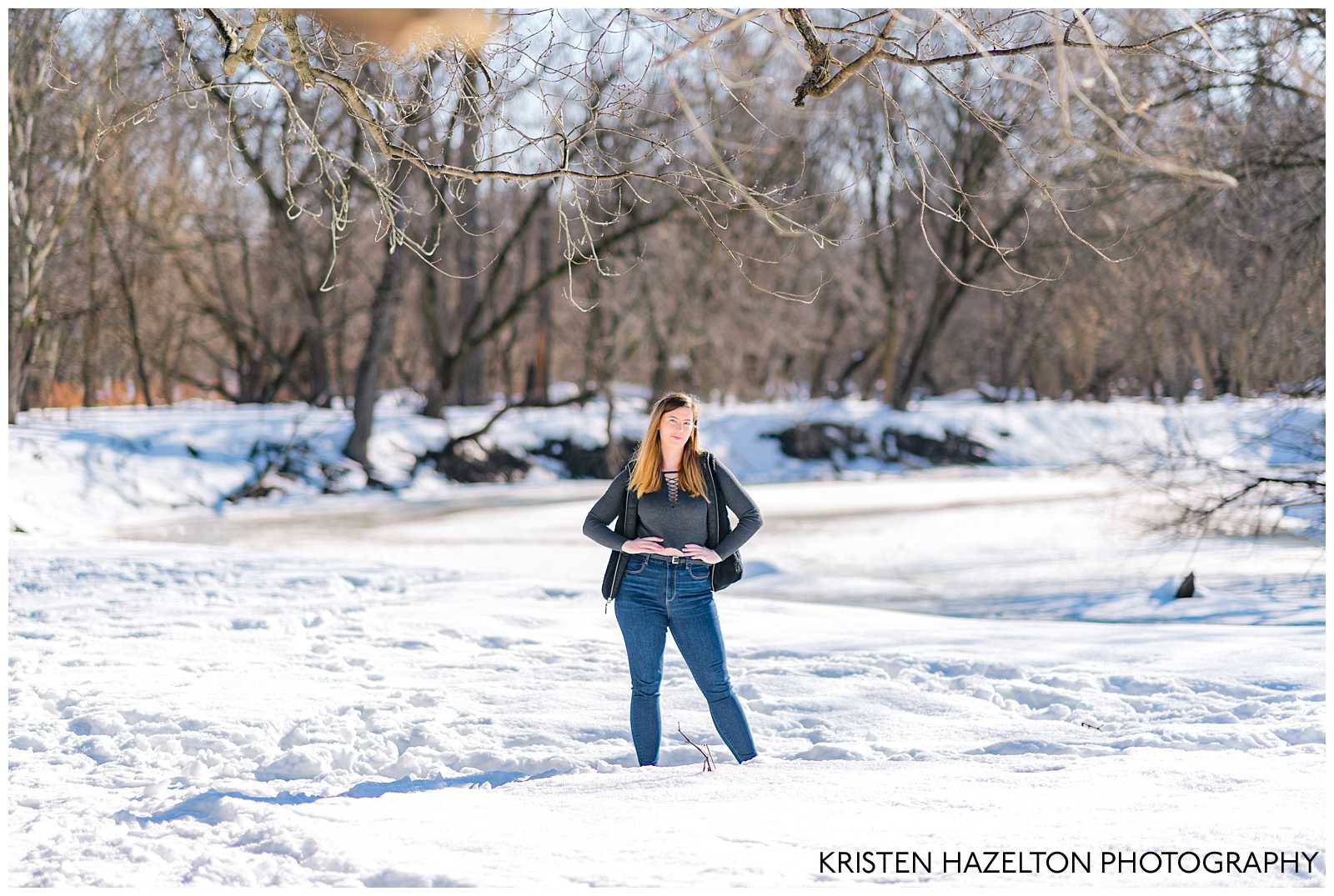 Winter senior photos of a college senior girl posing in front of a frozen river