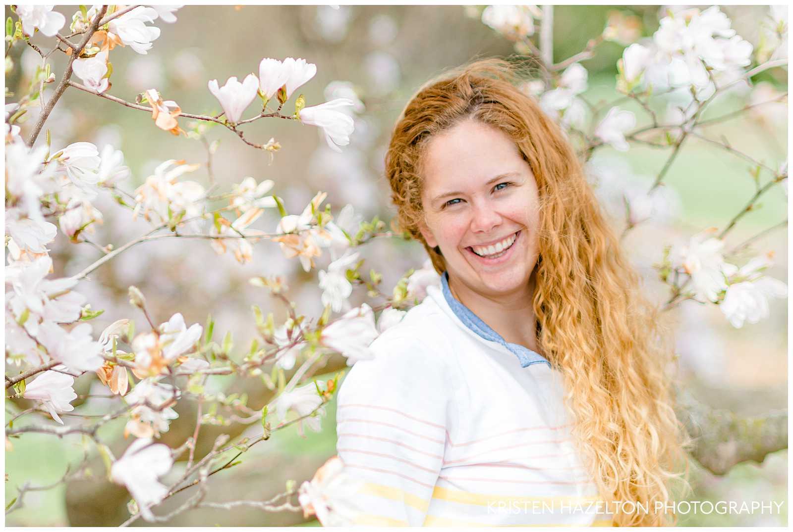 Portrait of a Redheaded woman smiling in front of white star magnolias