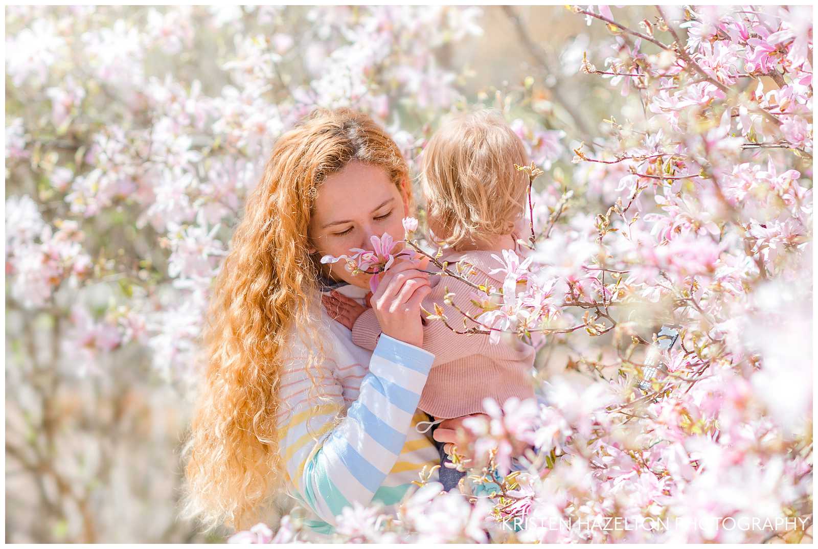 Redheaded woman smelling a magnolia at a spring motherhood photo shoot