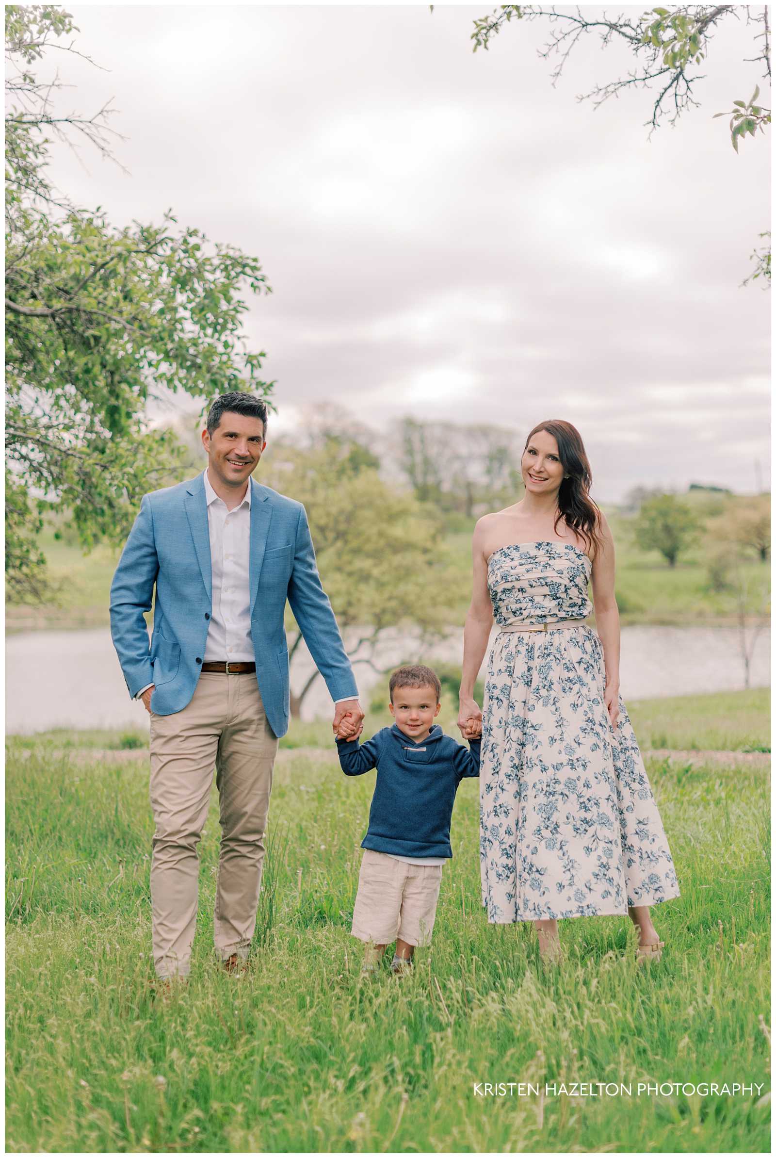 Family of three standing on a hill at the Morton Arboretum in the spring time for their family photos by Chicago family photographer Kristen Hazelton