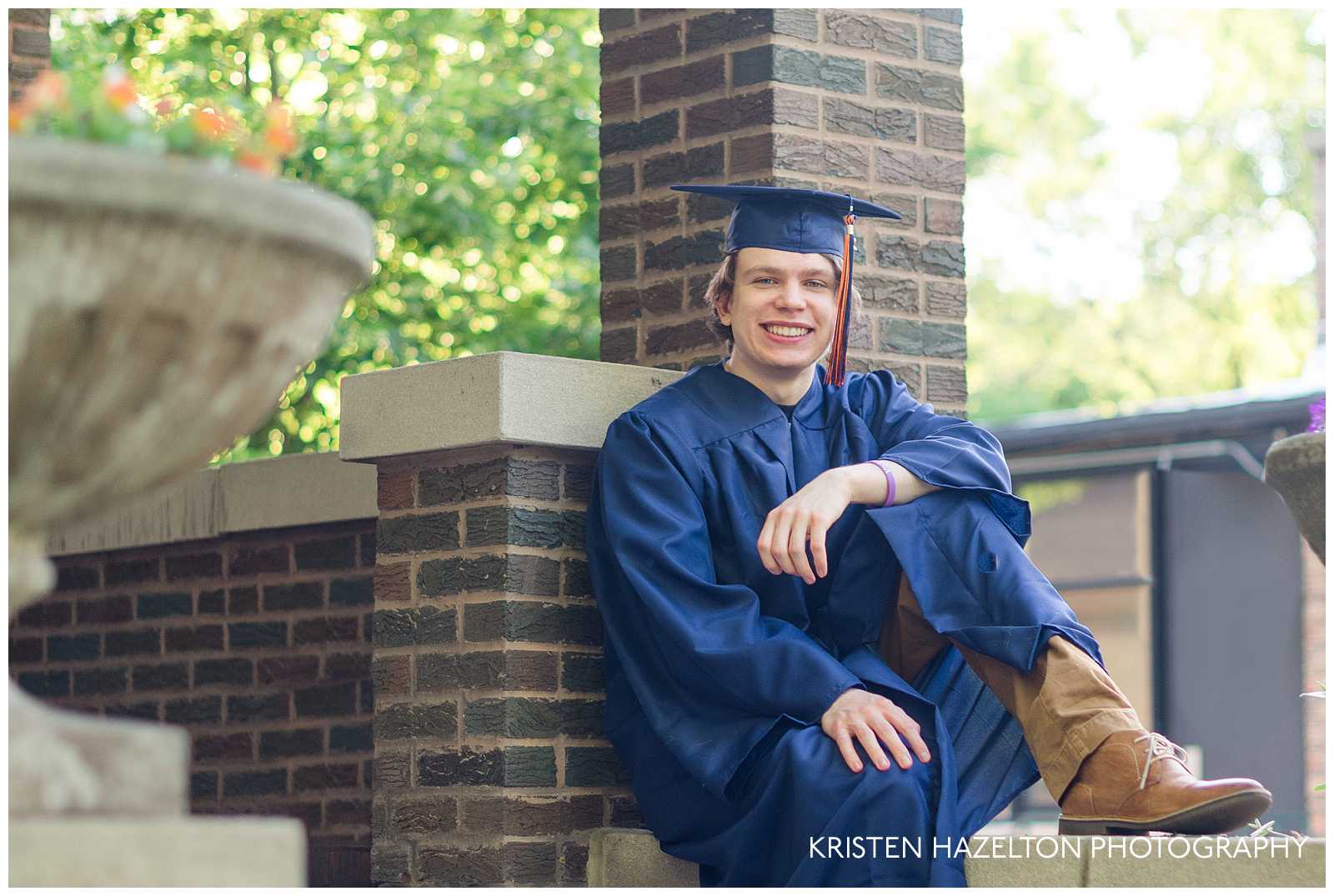 High school graduate wearing cap and gown and sitting on a stair ledge.