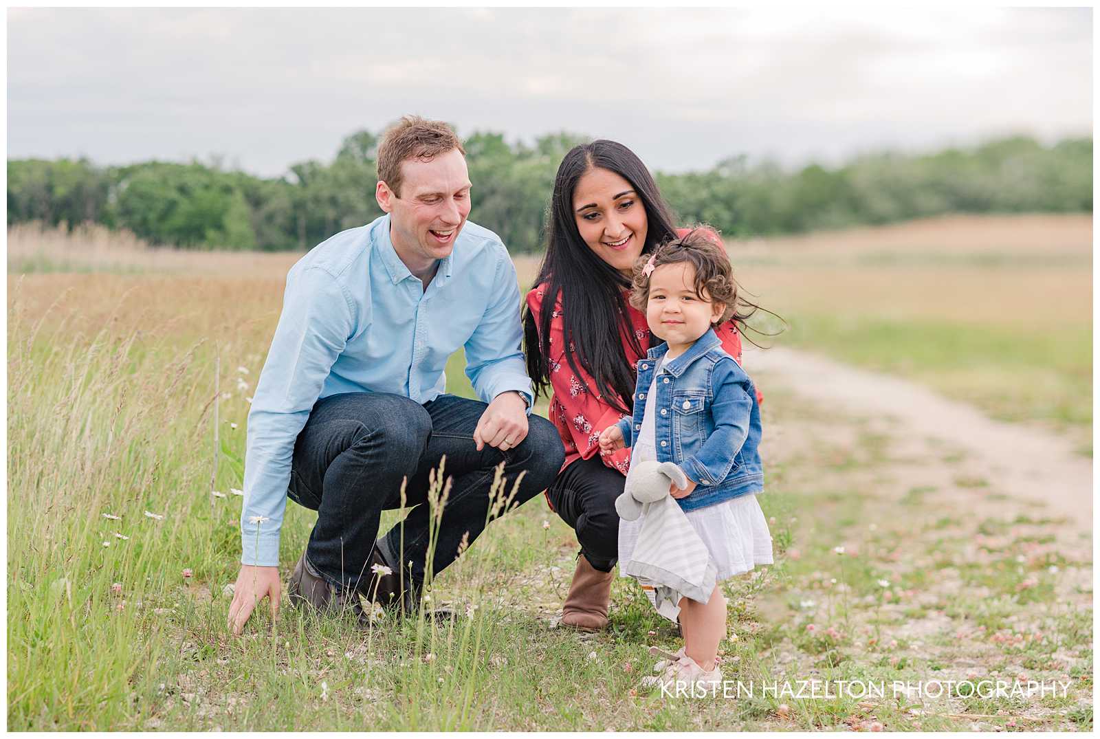 Happy family of three crouching in a meadow by Forest Park, IL photographer Kristen Hazelton