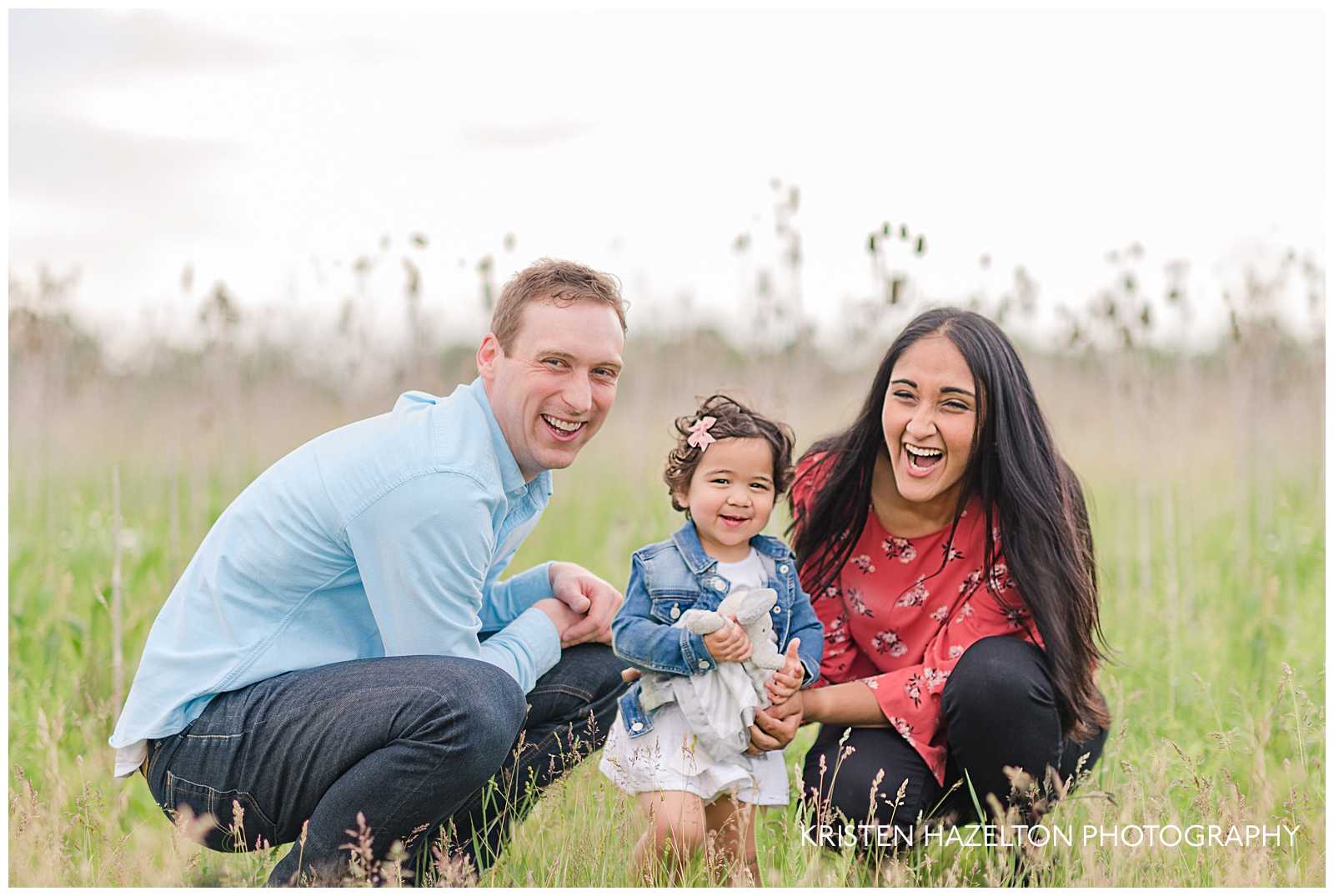 Young family of three crouching in a meadow by Forest Park, IL photographer Kristen Hazelton