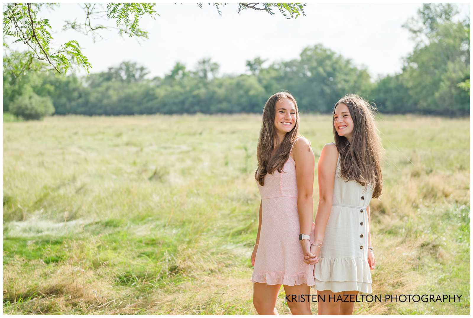 Two teenage sisters standing back to back in a field