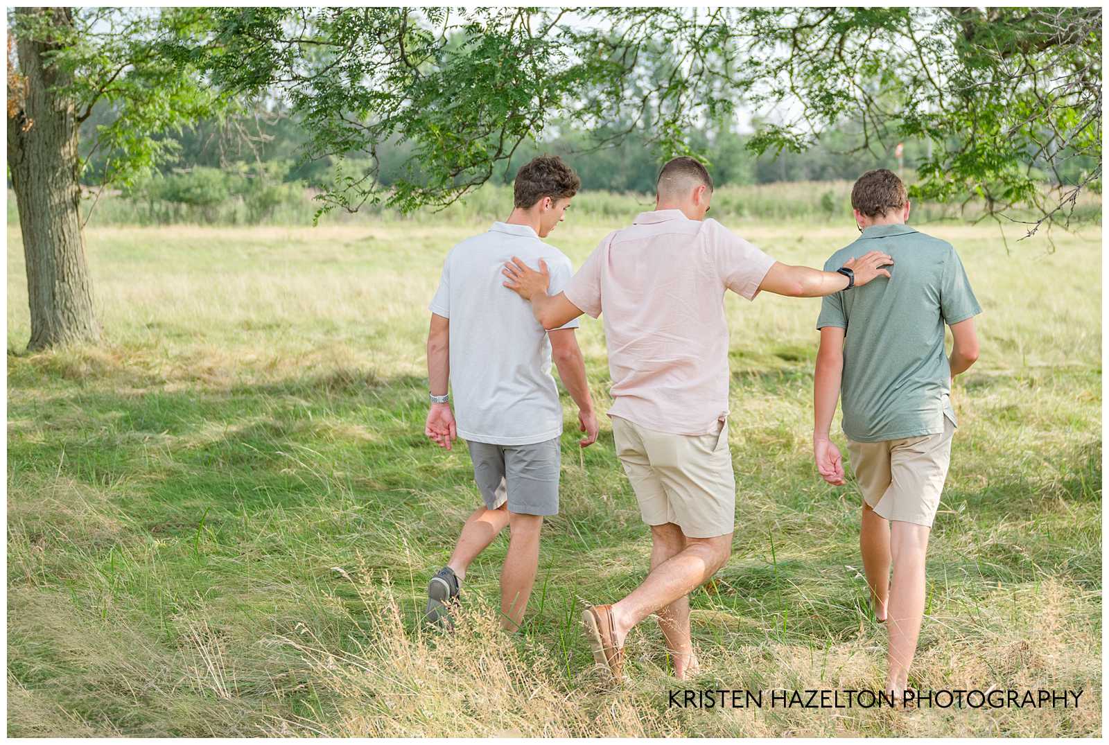 Three teenage boys walking in a field by Elmhurst, IL photographer Kristen Hazelton