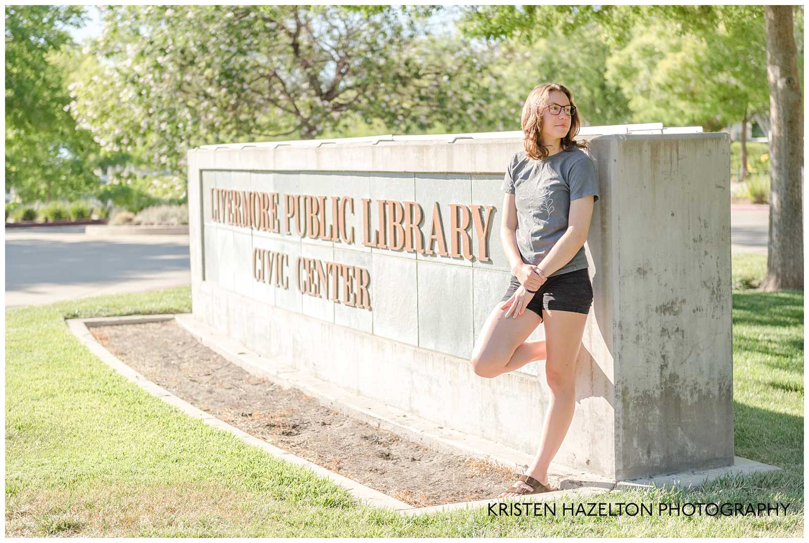 High school senior girl standing next to the Livermore Public Library Civic Center sign 
for her Senior Portraits