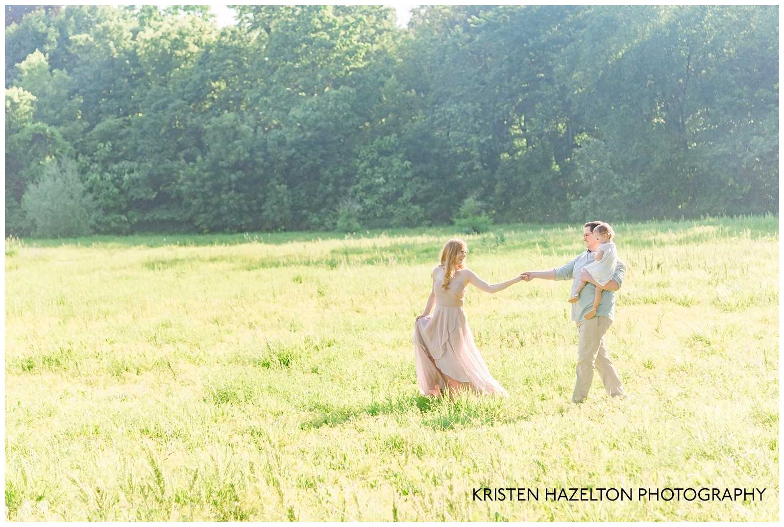Woman leading her husband and baby daughter through a sunny meadow by Riverside, IL family photographer Kristen Hazelton