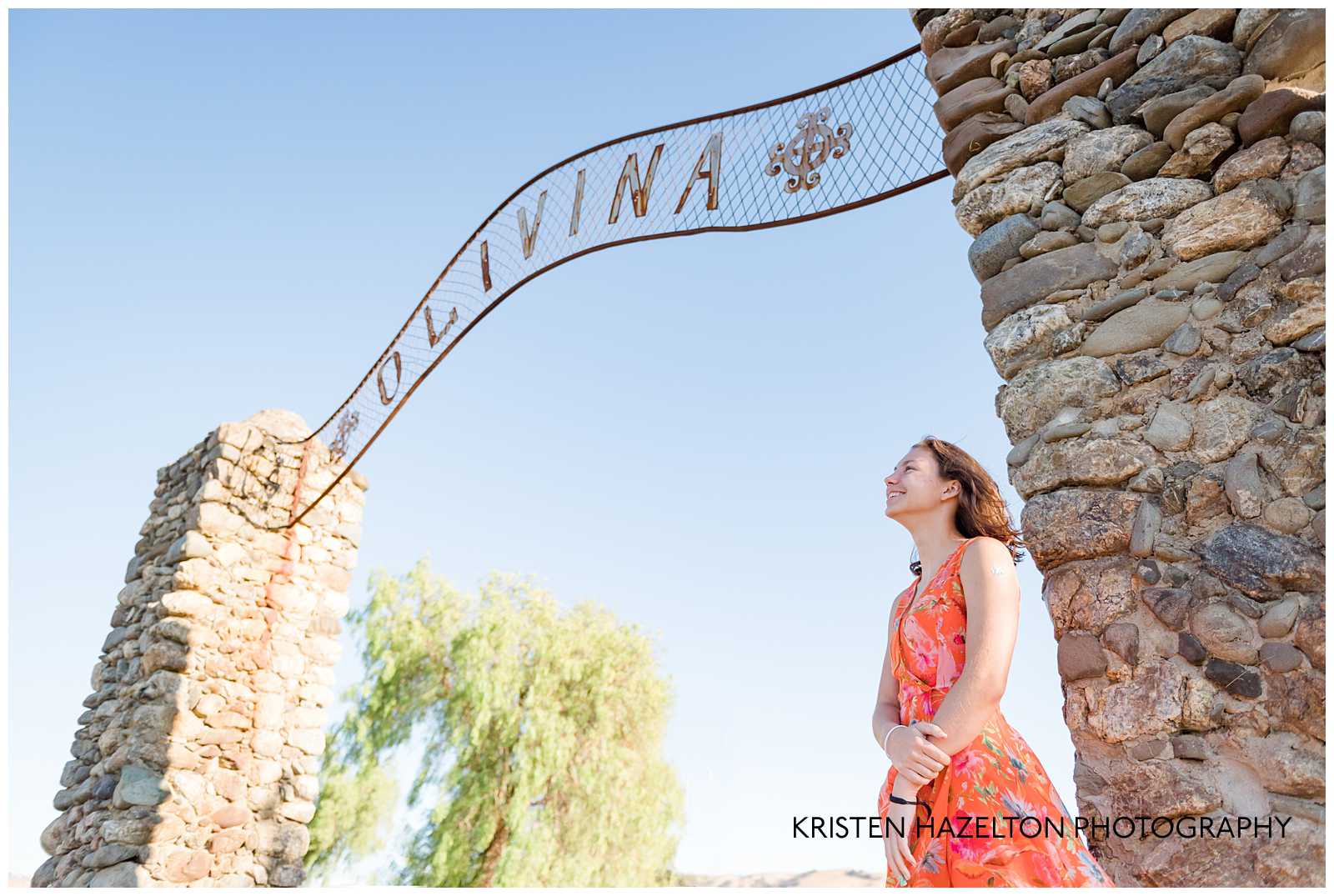 High school senior girl standing under a sign that reads "Olivina" in Livermore, CA