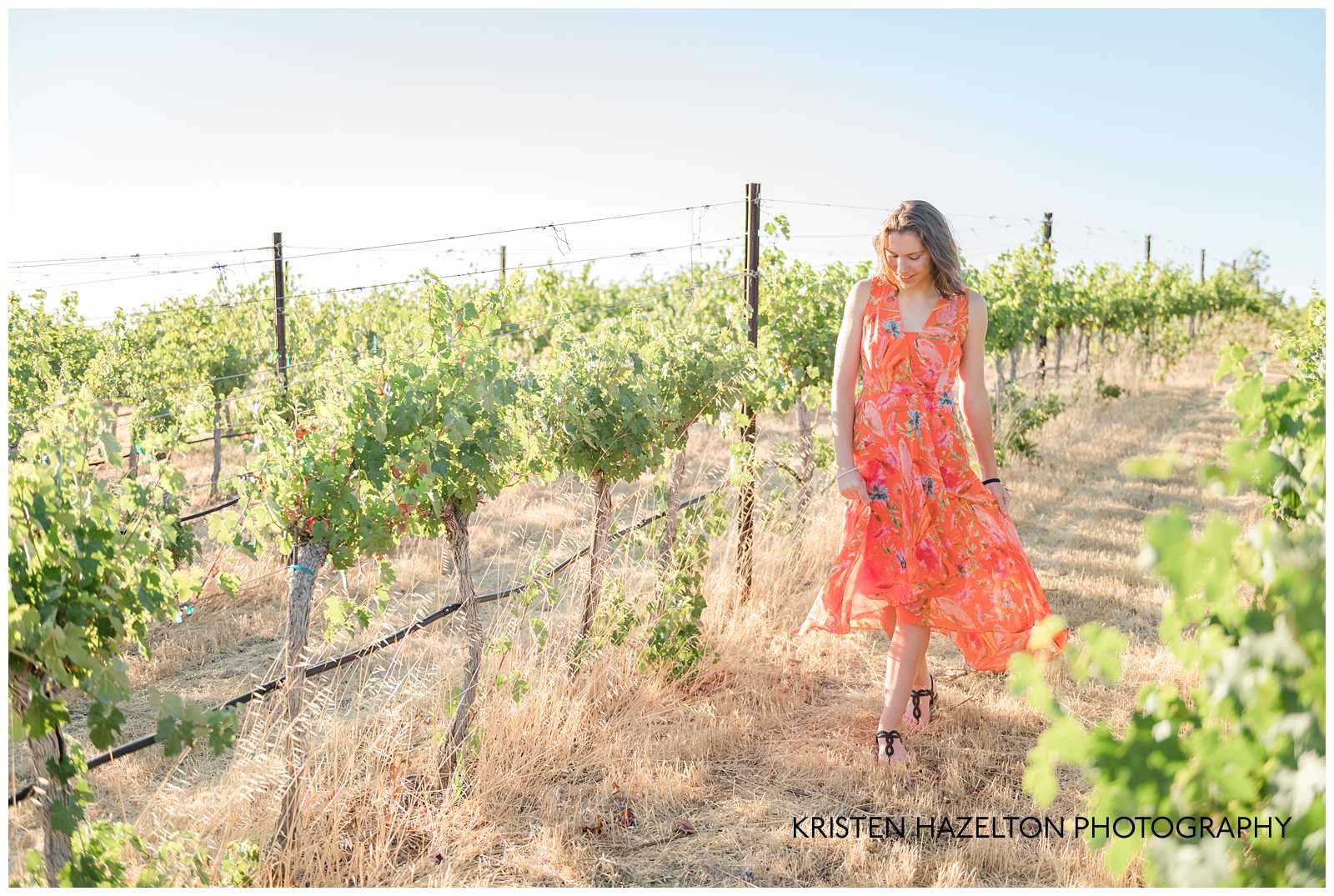 Girl in orange dress walking through a vineyard by Livermore photographer Kristen Hazelton