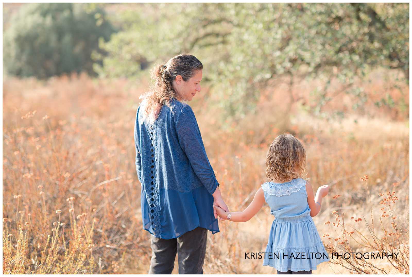 Mom and daughter walking through a field