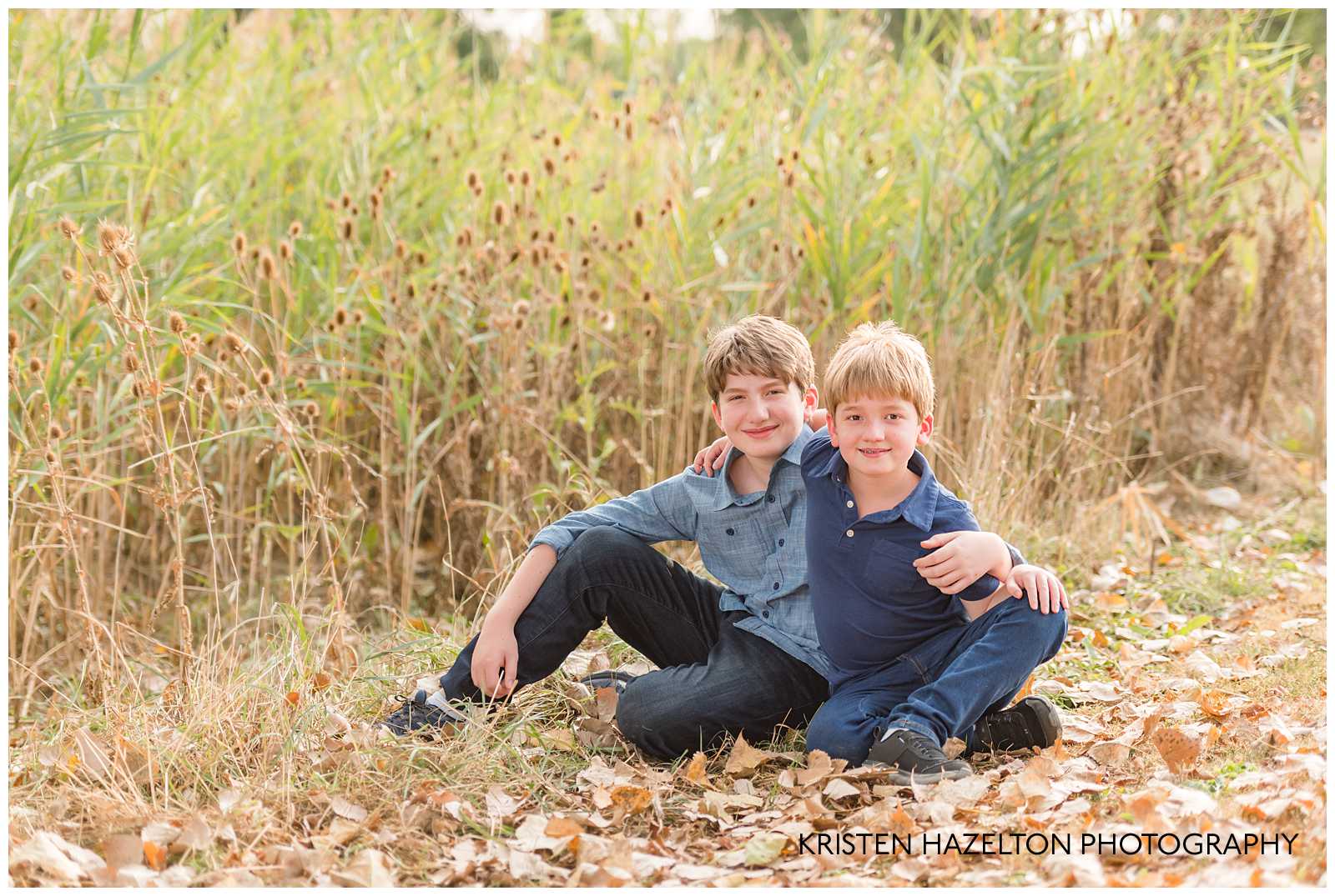 Two brothers seated next to some cattails