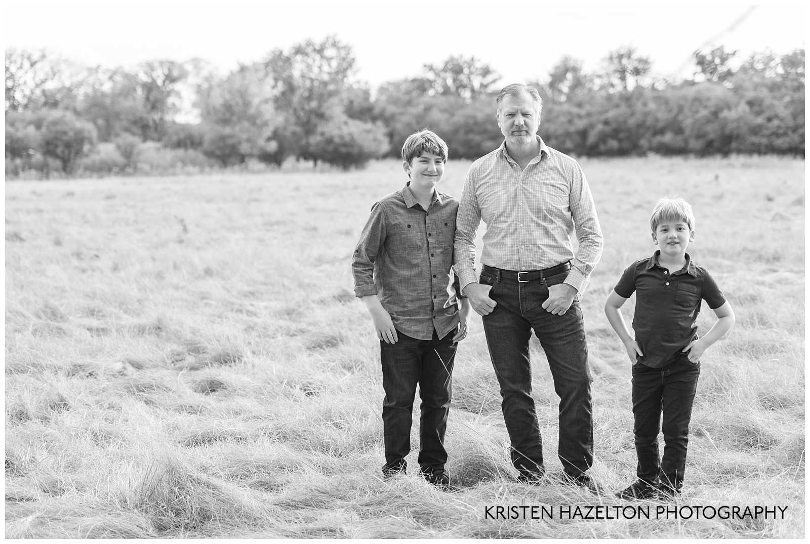 Black and white photo of Dad with young sons with hands on their hips.