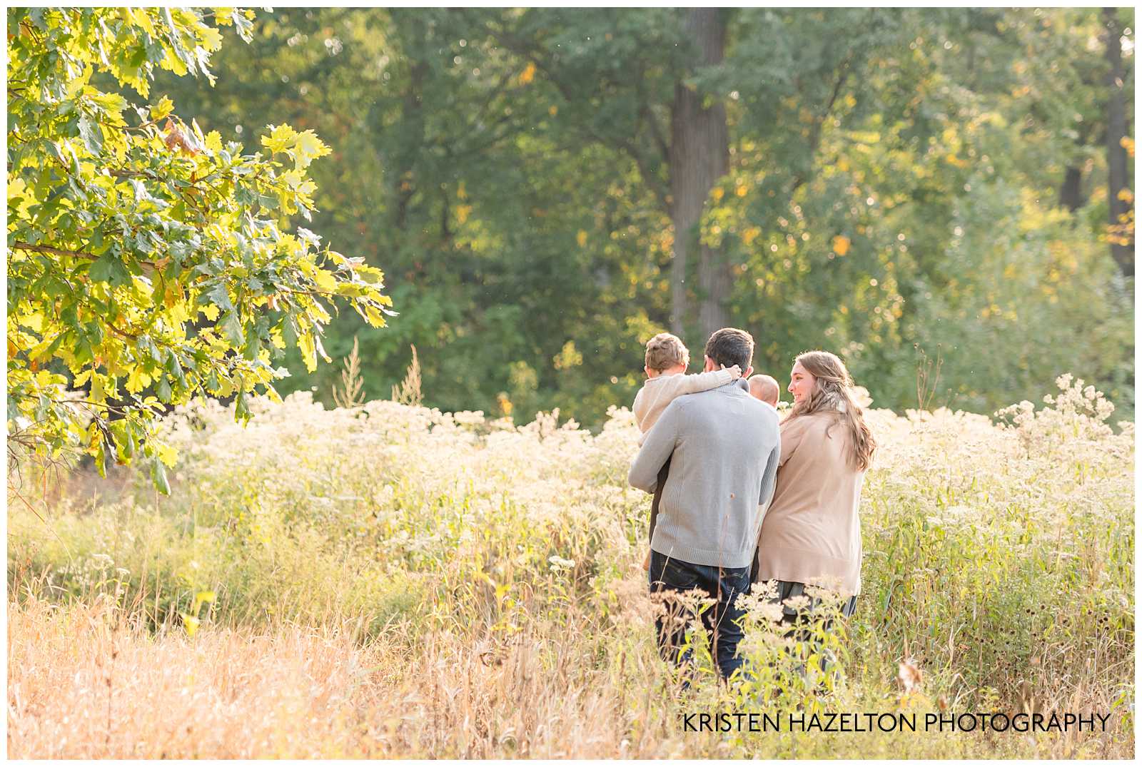 Young family of four walking in a meadow by Riverside, IL photographer Kristen Hazelton