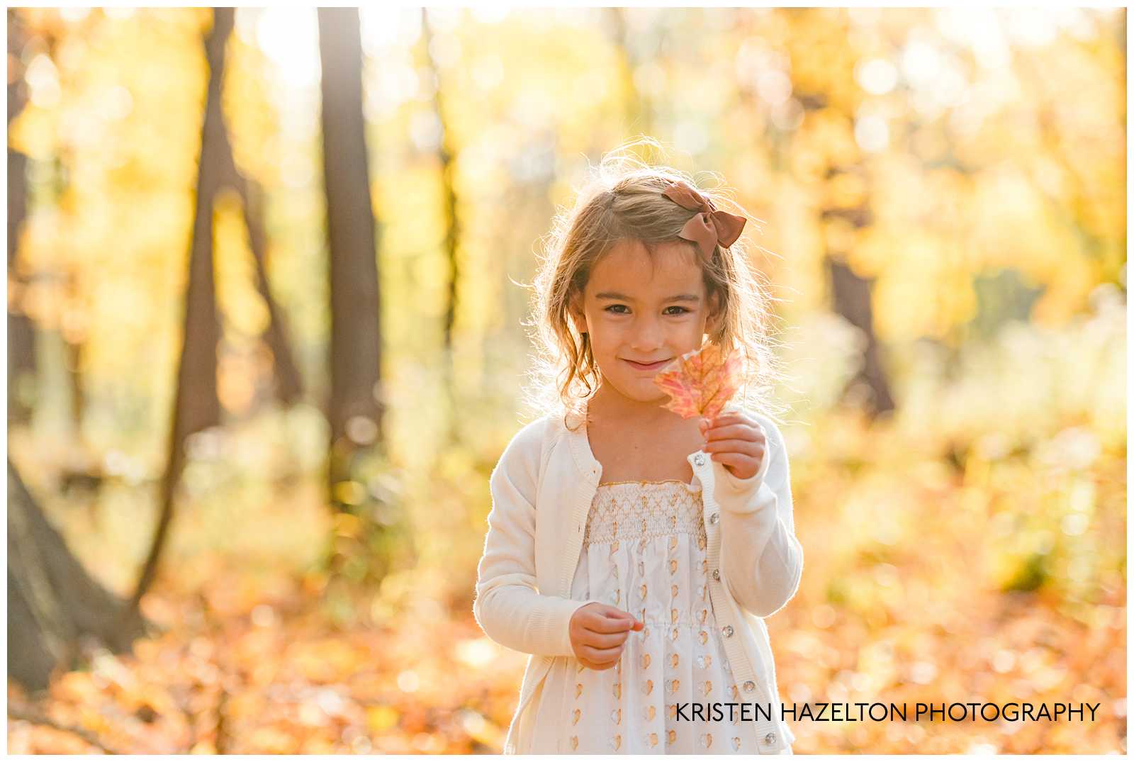 girl holding a leaf in the woods at photographer Kristen Hazelton's River Forest IL Fall Mini Sessions