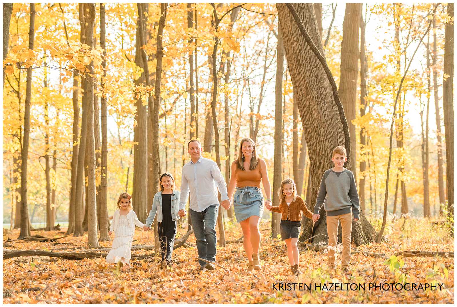 A family of six walking through the woods in fall at photographer Kristen Hazelton's River Forest IL Fall Mini Sessions